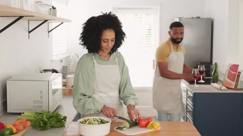 Un beso, cocina y una pareja negra brindan con vino mientras cortan verduras para que quede delicioso