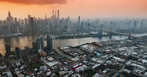 Hazy scenery of New York at sun setting hour. Stunning skyscrapers under the orange sky.