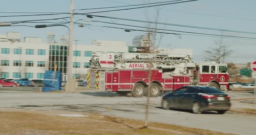 Fire Engine Driving Through City Street on Sunny Day