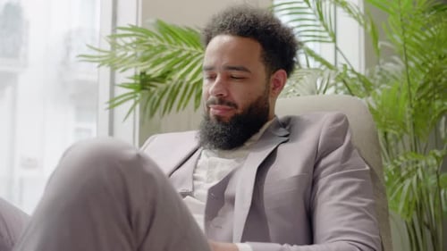 A Professional African American Man is in a Sleek Modern Office Focused on His Work