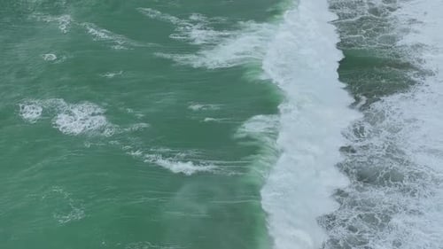 Aerial Video Towering Ocean Waves and Intricate Foam Patterns Dynamically Transform the Scenic Beach