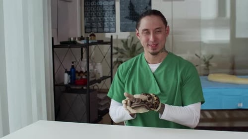 Retrato de un veterinario posando con una serpiente pitón en la clínica