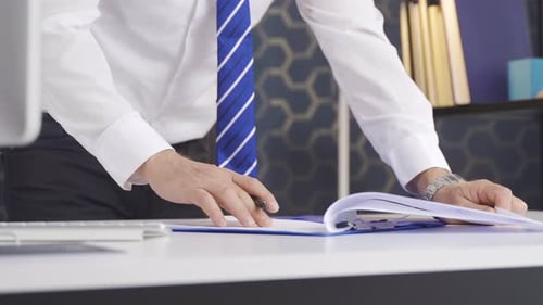 Close-up of a businessman's hands signing a contract in a modern workplace.