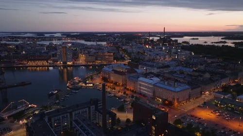 Forwards Fly Above City at Dusk Cars Driving on Waterfront Road Modern Buildings in Former Port