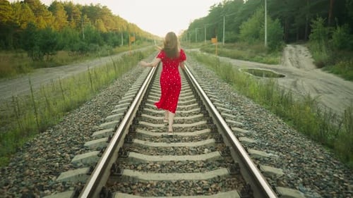 Woman in Red Dress Running on Railway Track Through Countryside