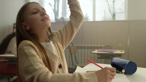 Girl raising her hand in class at school