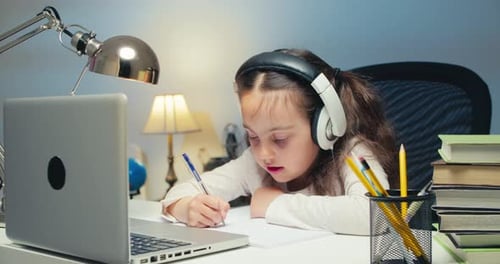 Child Studying with Laptop and Writing at Desk