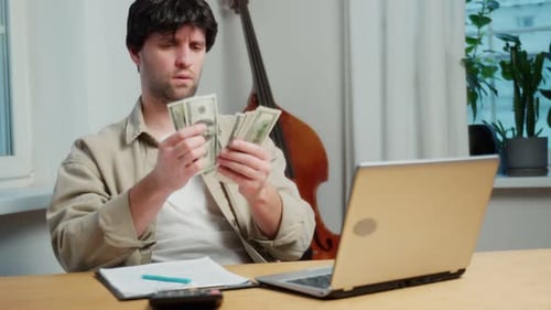 Blackhaired Business Consultant Counts Money in the Office and Writes Something Down in a Notebook