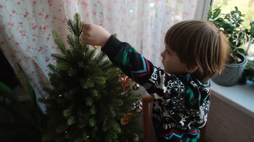Child Decorates Christmas Tree at Home