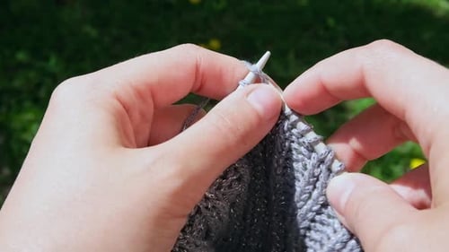 Close Up of a Woman Knits Wool Creating a Warm Gray Handmade Sweater with Her Hands and Sewing