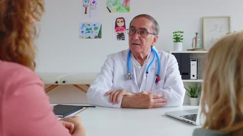 Pediatrician Talking with Mother and Child Girl at Doctor's Office