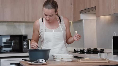 Woman Prepares Food and Tastes in Kitchen
