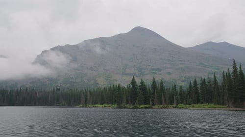 Cloudy summer day at a peaceful forest lake near Montana’s mountain ranges