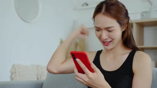 Woman Cheering While Using Her Smartphone Indoors