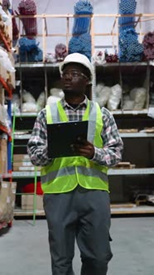 Warehouse Worker Walking Through Aisle with Clipboard