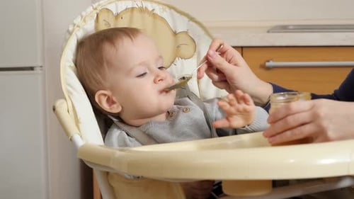 Adorable Baby Eats Food in Highchair