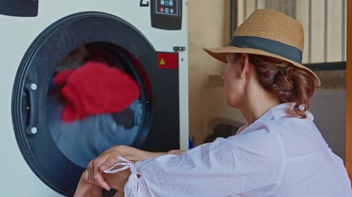 Woman Watches Clothes Tumble in Washing Machine