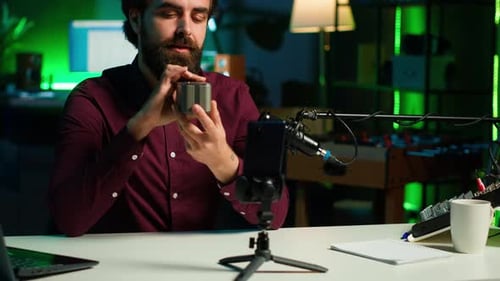 Man Reviews Speaker on Smartphone in Dim Room