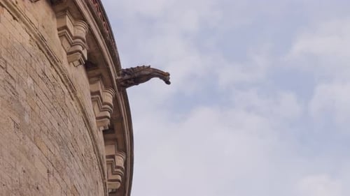 Gothic gargoyle on historic stone facade in Amboise, France against a cloudy blue sky