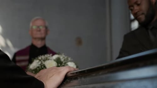 Unrecognisable Man Putting Hands on Coffin Lid at Memorial Service