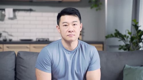Portrait of an Asian young adult man in home casual clothes who confidently looks at the camera