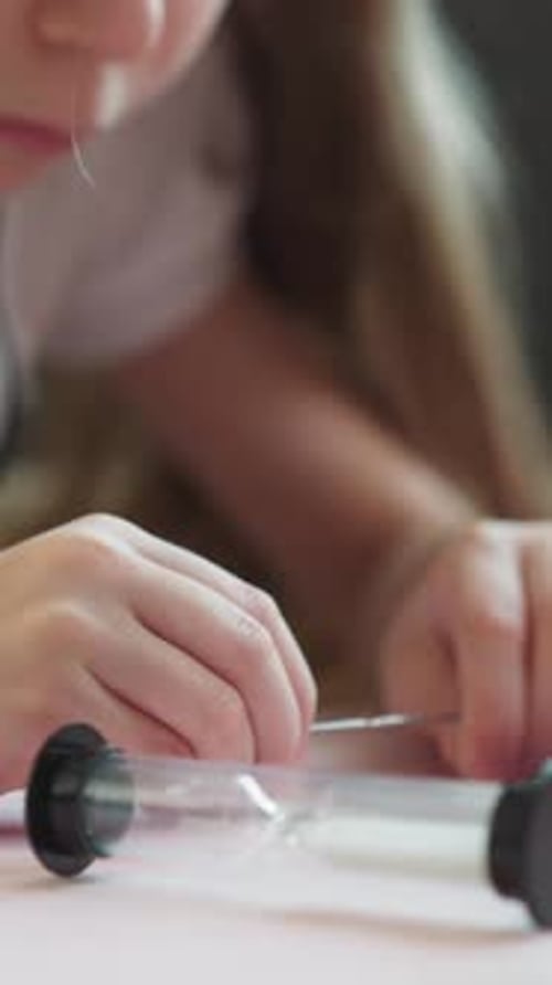 Child Moving Powder in an Hourglass with Tool