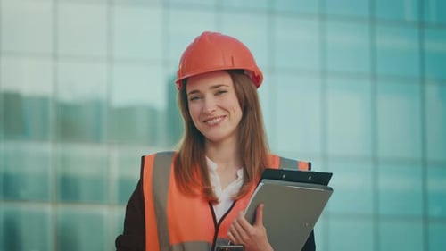 Successful Female Engineer or Architect Wearing Orange Helmet and Safety Jacket