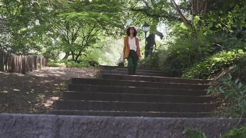 fashionable positive Brazilian lady woman walking down the stairs of a city park on a sunny day