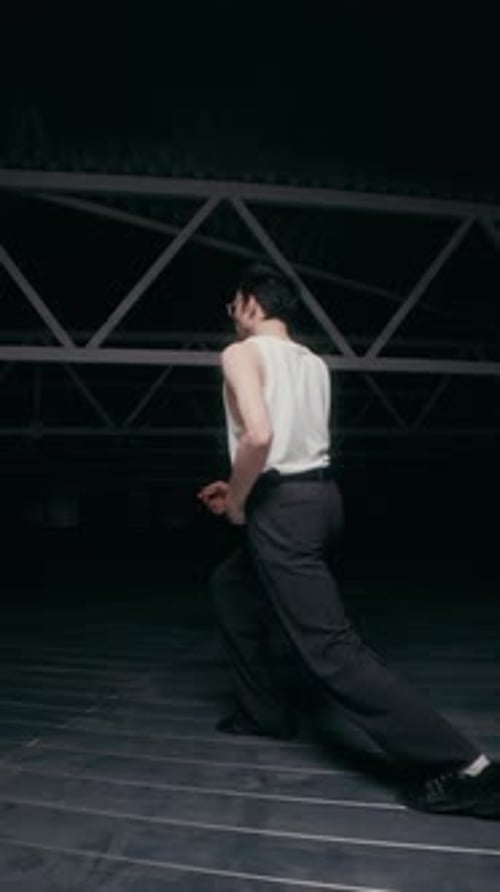 Joven bailarina contemporánea actuando en un oscuro espacio industrial