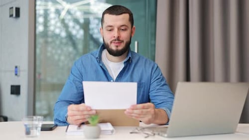 Excited Man Reads Good News in Office Letter