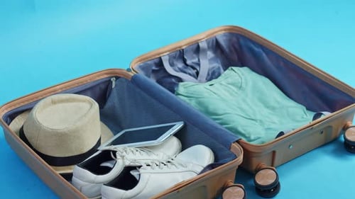 Stop-motion of suitcase being packed with travel essentials like clothes, shoes, and tech
