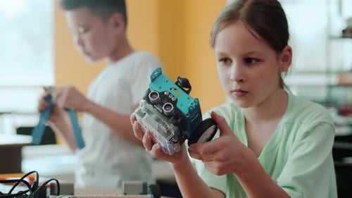 Girl Examining Her Robot in a Classroom