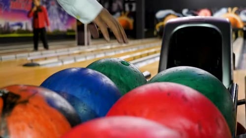 Spieler wählt eine Bowlingkugel und wirft sie die Bowlingbahn hinunter