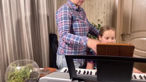 Woman Teaching Child to Play Piano