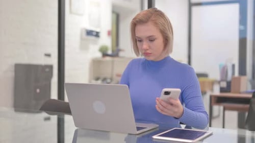 Young Woman Works with Laptop and Cellphone