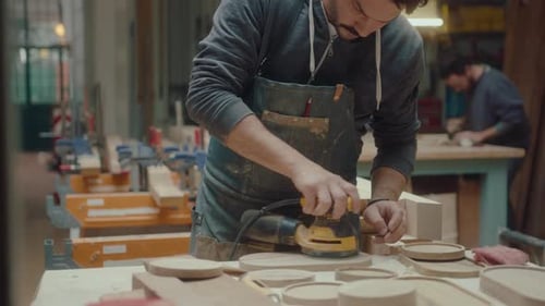 Man Sanding Wood in Brightly Lit Workshop