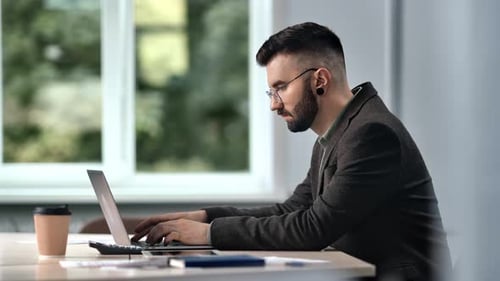 Bearded Male Skilled Manager Employee Working Laptop Chatting Online Desk Workplace at Office Window