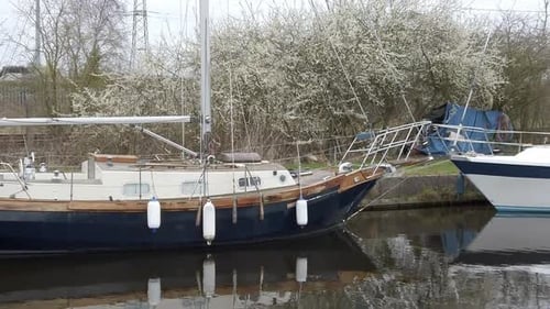 Small old blue sailboats moored on narrow rural countryside canal marina