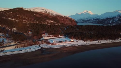 Vanlifers et campeurs séjournant sur la plage du fjord du nord de la Norvège. Les montagnes enneigées sont en arrière-plan et