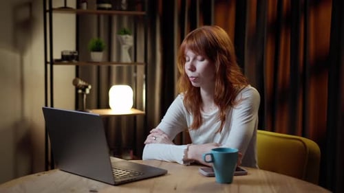 Young Woman Video Conferencing at Table with Laptop