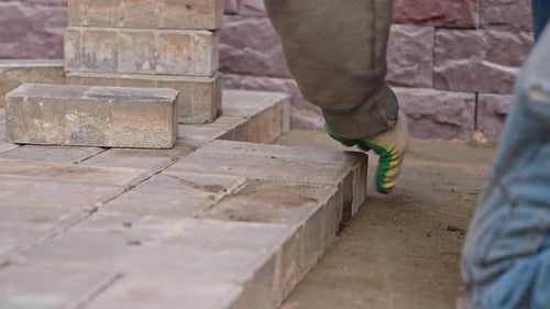 Closeup of a Worker Using a Mallet to Lay Paving Stones