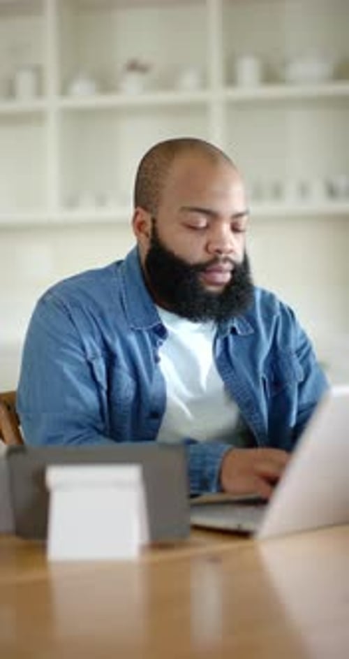 Vertical video: Man working at table typing on laptop, pausing, resuming as tech icons guide eyes