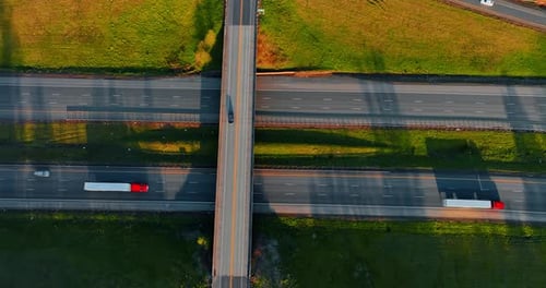 Speedway over the highways with some transport moving by. Drone footage above the roads at sunset.