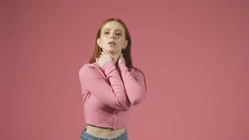 A Female Model with Long Red Hair Poses in Front of the Camera on an Isolated Background with a