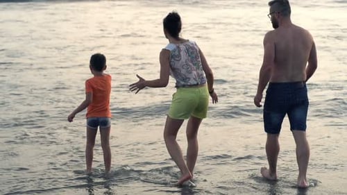 Happy family enjoys carefree summer vacations playing with waves at the sea shore