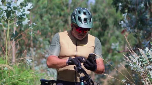 Senior cyclist using smartphone on electric mountain bike