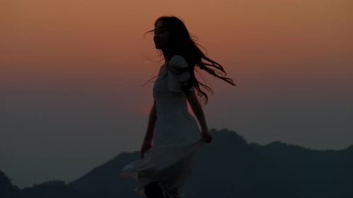 woman girl wearing long dress dancing alone during the sunset in mountain landscape slow motion