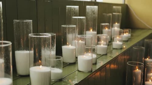 Burning Candles in Clear Glass Vases on Shelf