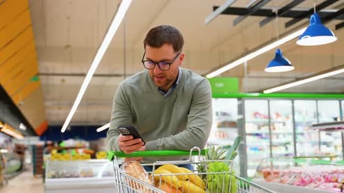 Man Checking Grocery List on Phone While Shopping