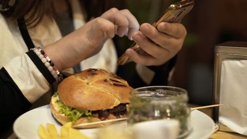Teenage girl enjoying lunch with smartphone in a cafe